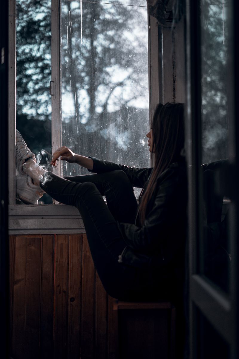 Person sitzt nachdenklich am Fenster im warmen Licht, Symbolbild für Depression und Genesung