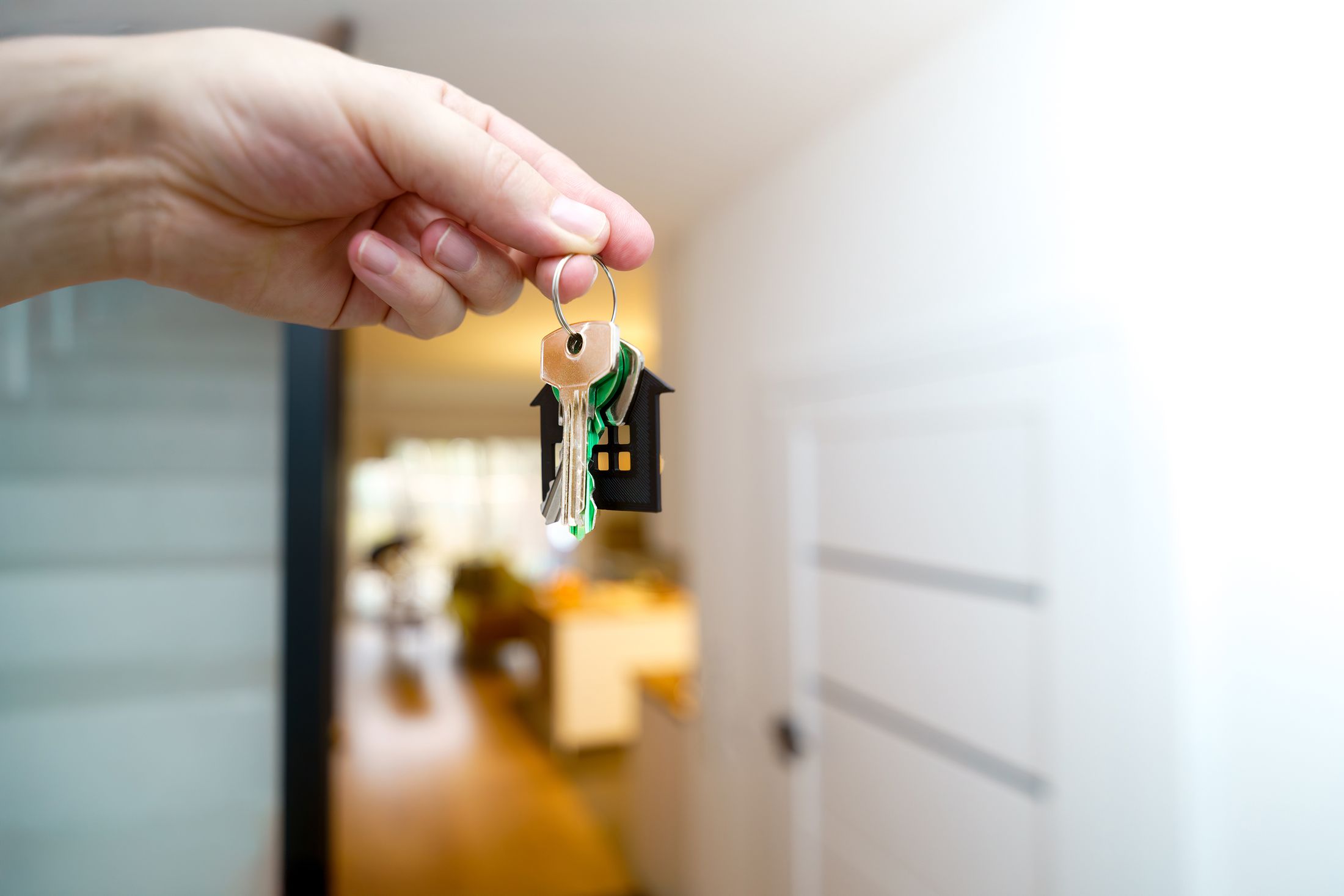 Hand hält Hausschlüssel in einer modernen Wohnung vor unscharfem Hintergrund