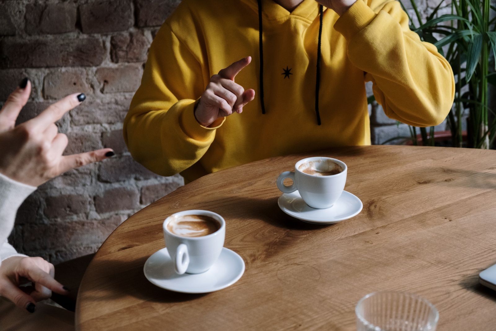 Zwei Personen unterhalten sich in Gebärdensprache bei Kaffee in einem Café