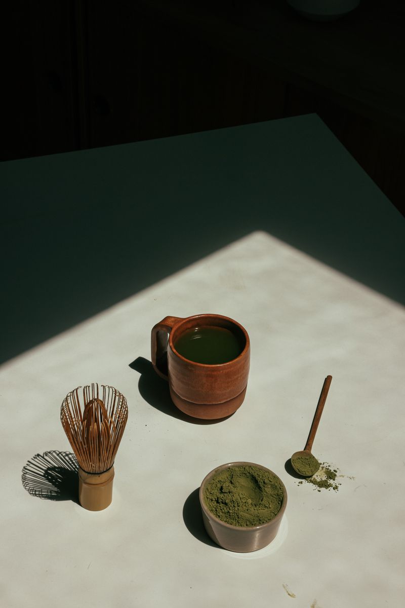 Grünes Matcha-Pulver mit Bambusbesen bei stimmungsvollem Licht