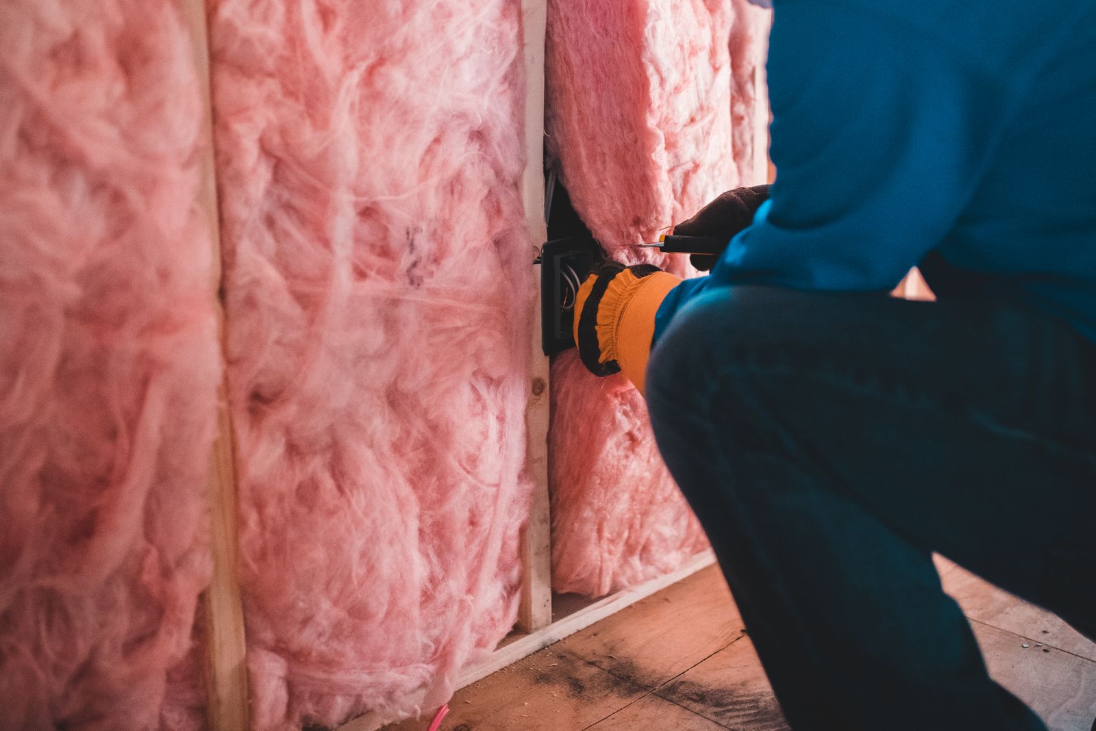 Handwerker installiert rosafarbenes Dämmmaterial in einer Hauswand