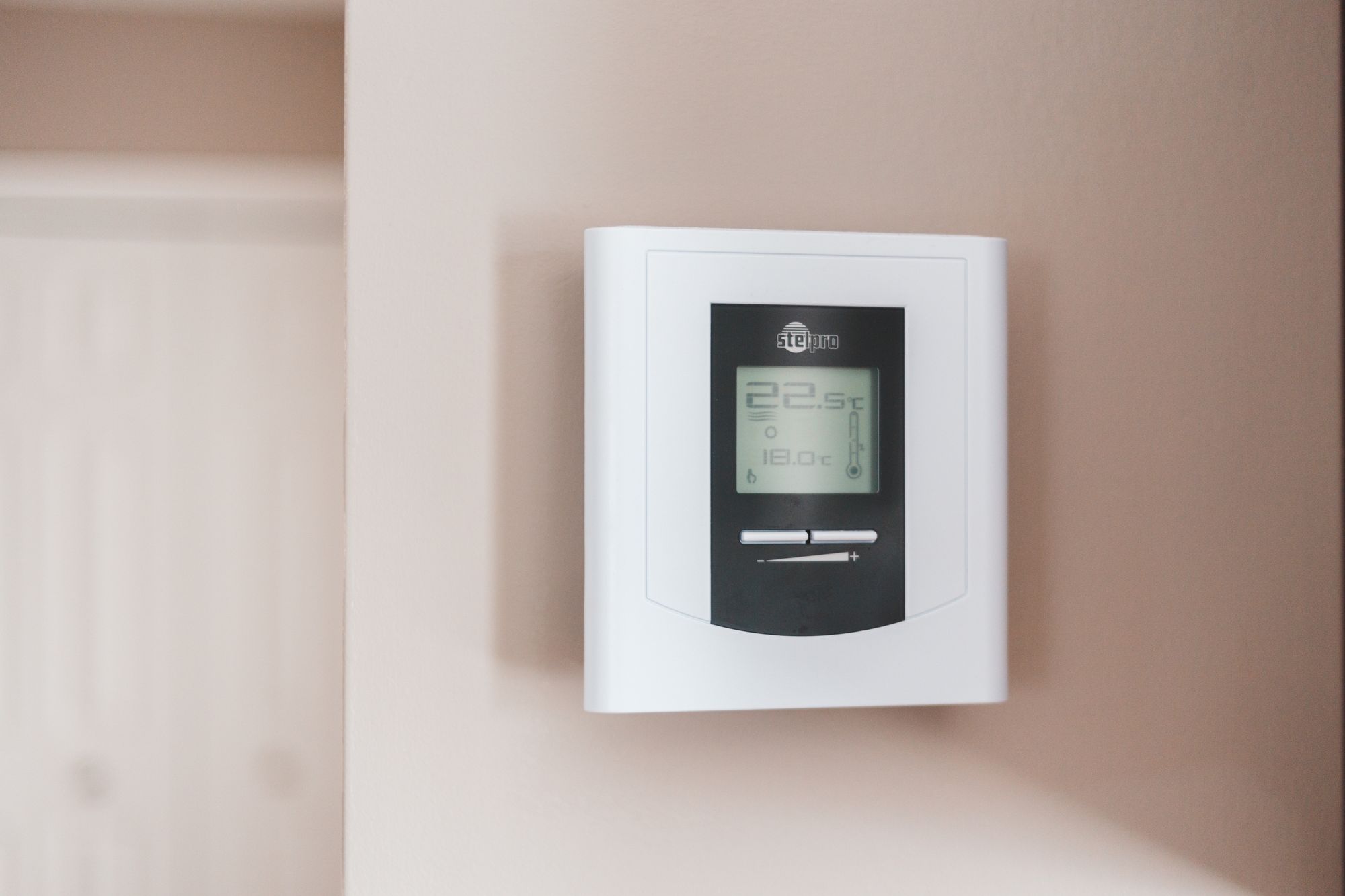 Digitales Thermostat an einer hellen Wand zeigt die eingestellte Temperatur