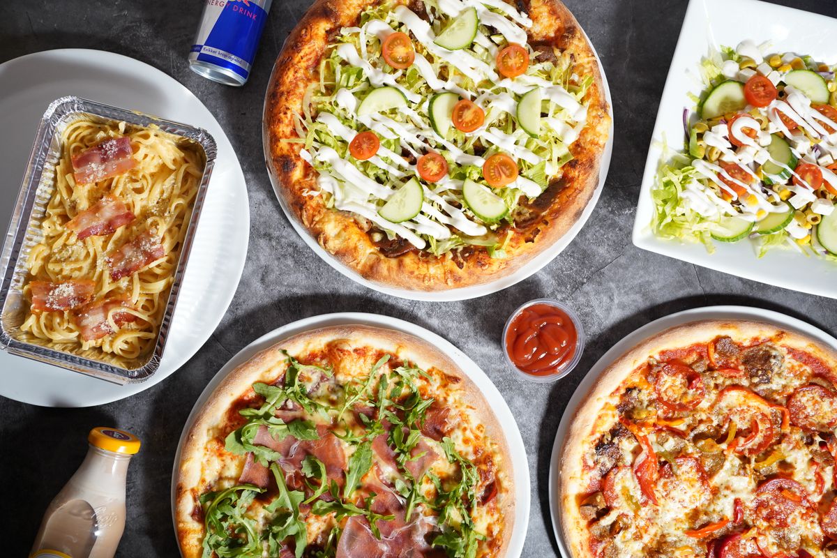 Gedeckter Tisch mit italienischen Gerichten, Pasta, Pizza und Salat