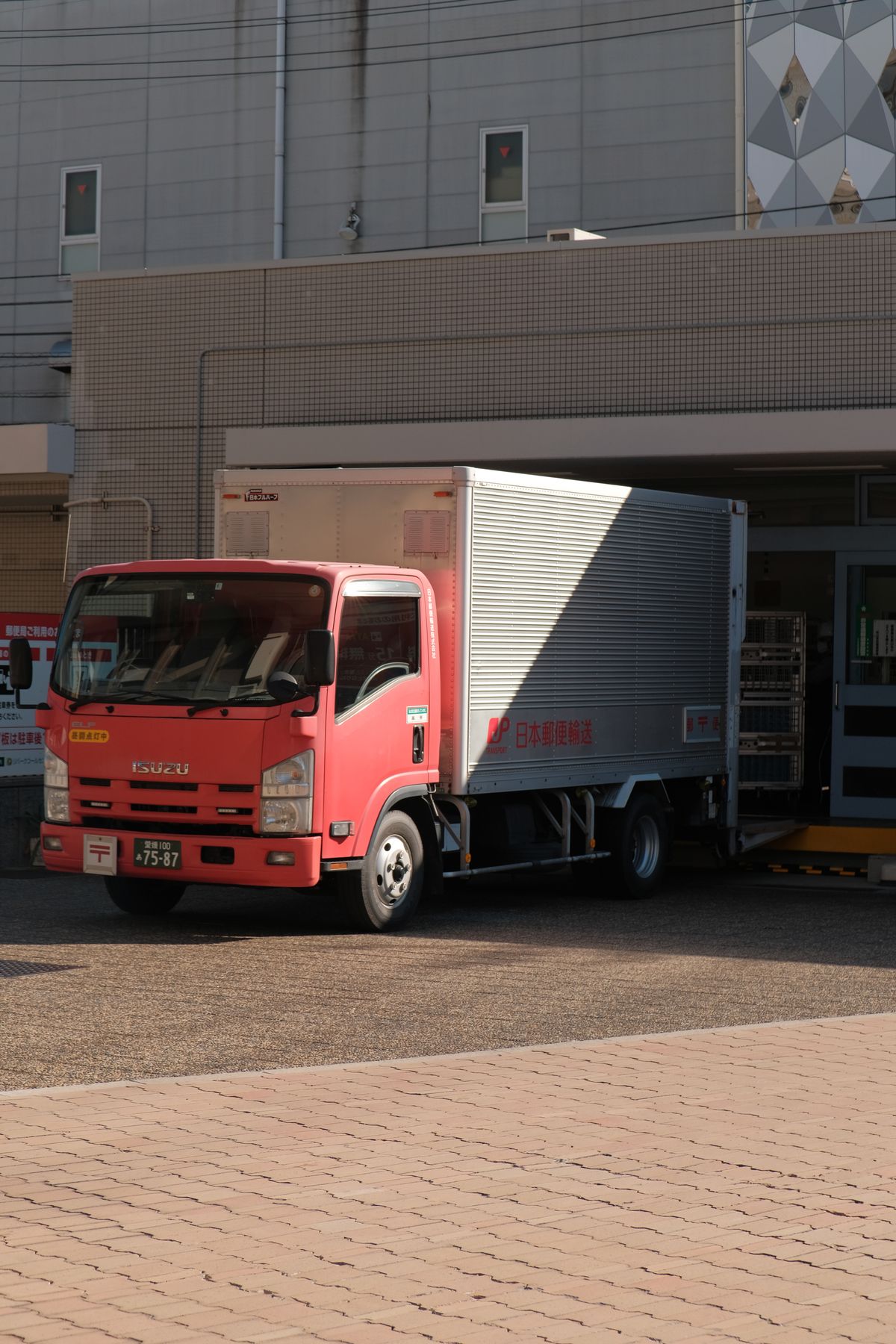 Roter Lieferwagen beim Entladen von Waren an einer Lagerhalle