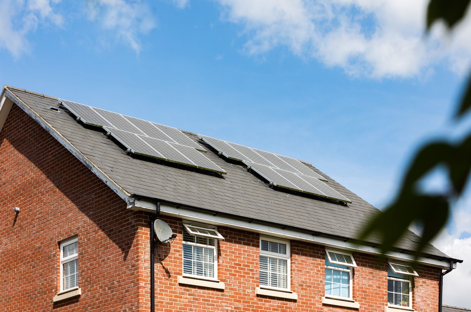 Backsteinhaus mit Photovoltaikanlage auf dem Dach unter klarem blauem Himmel