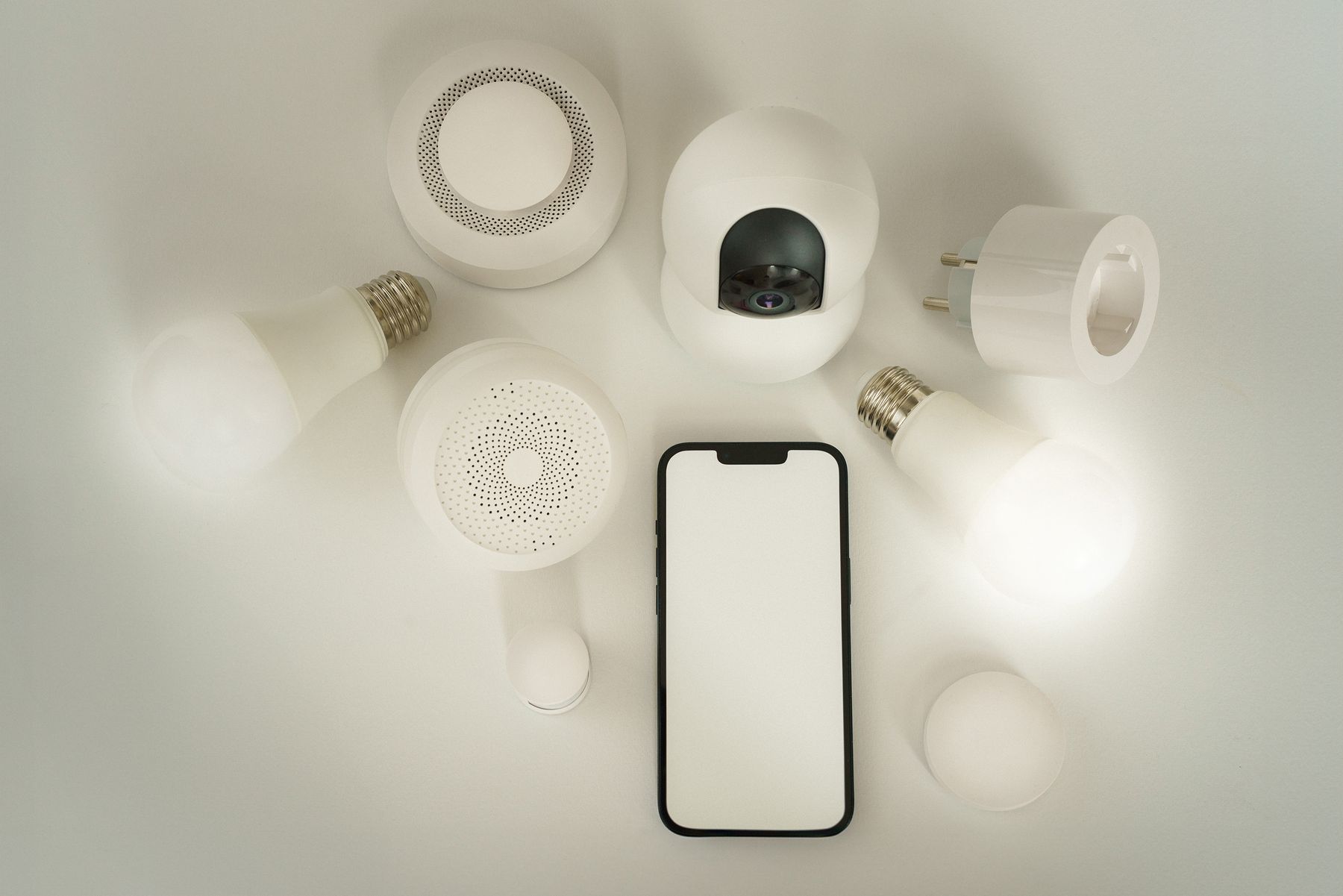 Smarte Rauchmelder und Smart-Home-Sensoren neben Smartphone und Leuchtmitteln
