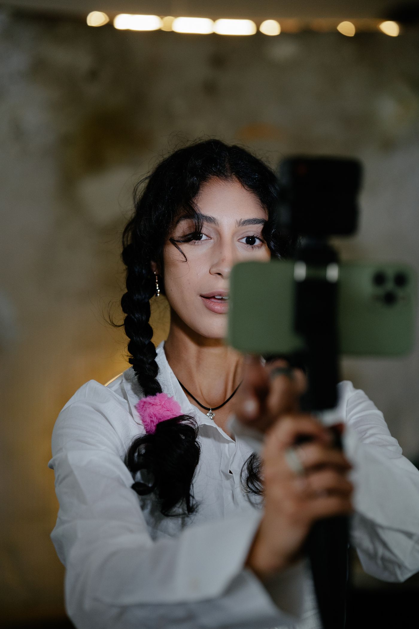 Frau mit Smartphone-Stabilizer filmt Video-Content in einem modernen Studio