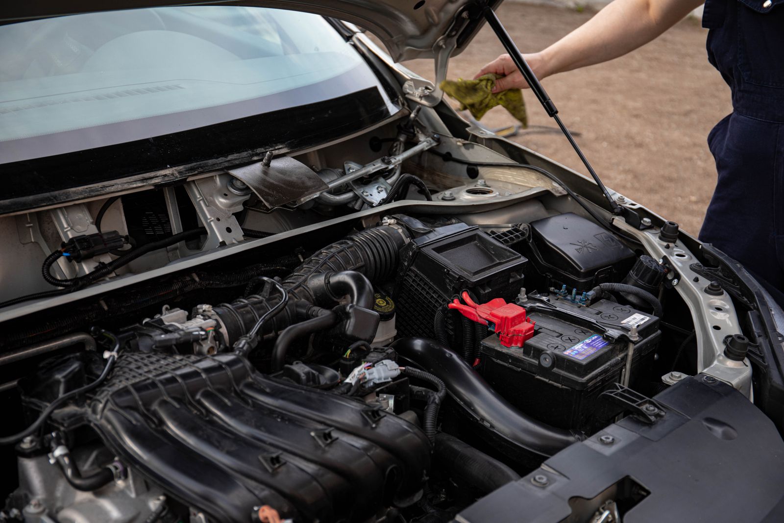 Blick in den geöffneten Motorraum eines Autos bei der Inspektion von Batterie und Motor