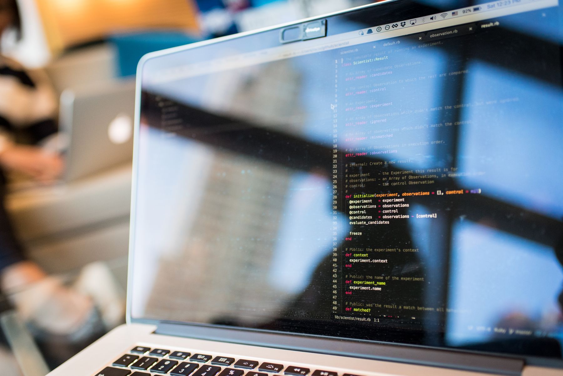 Frau sitzt an einem Schreibtisch und arbeitet an einem Laptop mit Code auf dem Bildschirm
