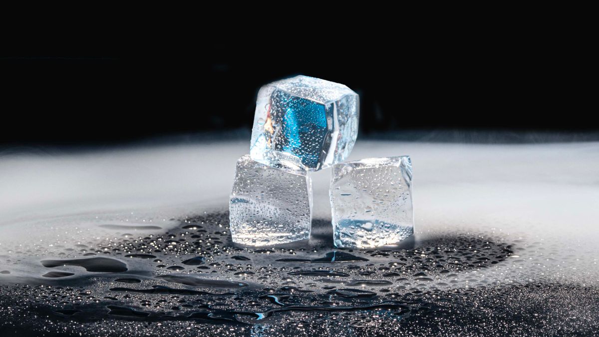 Drei schmelzende Eiswürfel auf einer dunklen, nassen Oberfläche